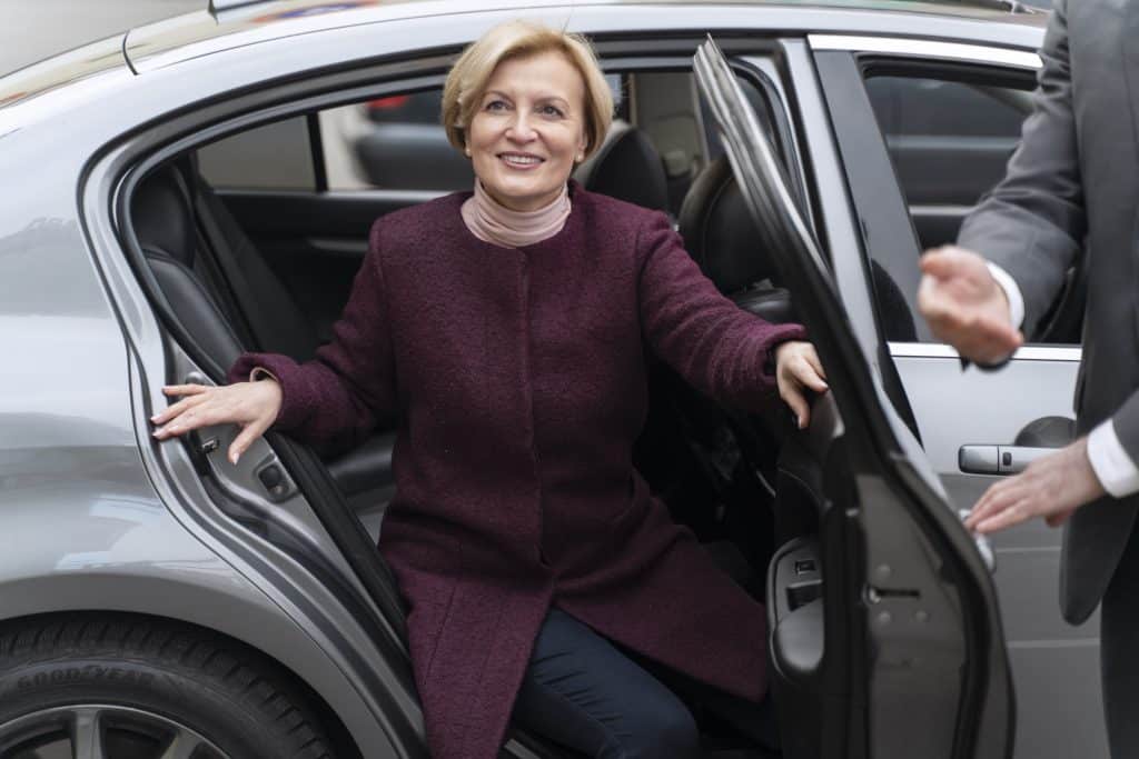 Taxifahrer hält der Dame die Tür auf.